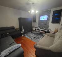 Living room with two sofas, a TV on the wall, and a wooden decor floor.