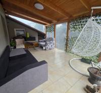 A terrace in a family house in Hont with a swing, a sofa, and a wicker chair.