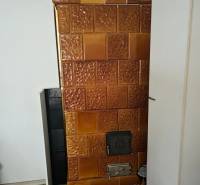 Tiled stove in a family house with a wood-patterned floor.