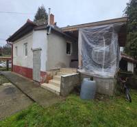 A family house in Hont with an unfinished facade, plastic windows, and stairs at the entrance.