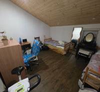 Attic room with a wooden ceiling, wooden decor flooring, bed, table, mirror.
