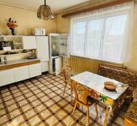 A kitchen in a family house with a dining area, a cabinet, and a refrigerator.