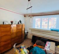 A room in a family house with wooden furniture, a chandelier, and a window with a view.
