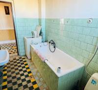 Bathroom in a family house with a bathtub, sink, and light green tiles.