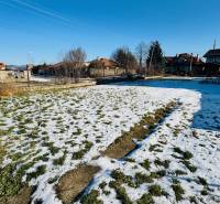A snow-covered plot of land behind a family house in Veľké Bielice in Partizánske, surrounded by houses.