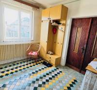 Entrance hall in a family house with a colorful tiled floor, a cabinet, and a wicker chair.