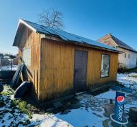 Behind the house in Partizánske, Veľké Bielice, there is a wooden cabin in the snowy yard.