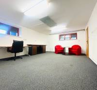 The office in the family house has a carpet, a desk, and red chairs.