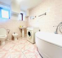 A bathroom in a family house with a bathtub, toilet, bidet, and washing machine.