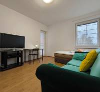 Living room in a family house with a sofa, television, table, and wooden decor flooring.