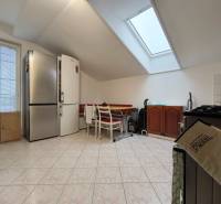 A kitchen in a family house with a sloped ceiling, a large refrigerator, and a dining table.