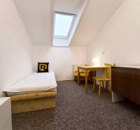 A simple room with a single bed, a table, and chairs in a family house.