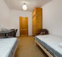 A room in a family house with beds, a table, a wardrobe, and a chair.