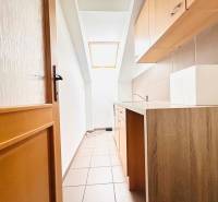 A narrow kitchen area in the office with a window and a wooden decor floor.
