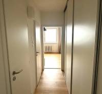 A hallway in a 3-room apartment with a wooden decor floor and white doors.