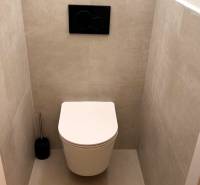 A bathroom with a wall-mounted toilet and gray tiles in a 3-room apartment.
