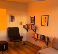 Living room in a 3-room apartment with an armchair, bookshelves, and a wooden decor floor.
