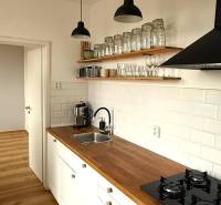 A kitchen with white cabinets, a wooden countertop, and a floor with a wood design.
