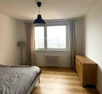 Bedroom with wood-patterned flooring, dresser, and bed in a 3-room apartment.