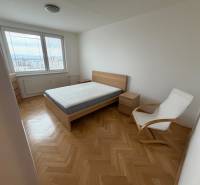 Bedroom with a bed, chair, and view. Floor with wood decor in a 3-room apartment.