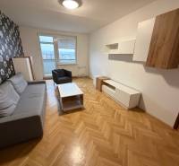 A living room in a 3-room apartment with a gray sofa and floral wallpaper on the wall.