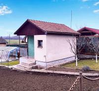 A cottage in Partizánske with a landscaped garden, greenhouse, and cultivation area.