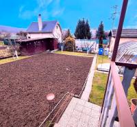 A garden with raised beds and trees around a cottage in Partizánske.
