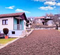 A cottage in Partizánske with a garden and freshly plowed soil, with a bench and shrubs.