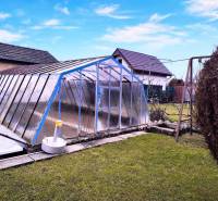 A garden in Partizánske with an above-ground pool covered by a structure, a swing, green lawn.