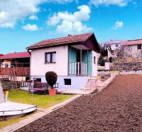 A cottage in Partizánske with a simple garden, curbs, and a gazebo under the blue sky.
