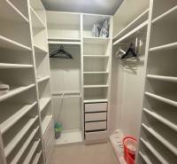 A wardrobe in a 3-room apartment with white shelves and wall hangers.