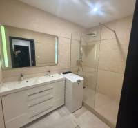 A bathroom with a double sink, shower, and washing machine in a 3-room apartment.