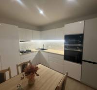 Modern kitchen in a 3-room apartment with white cabinets and marble tiles.