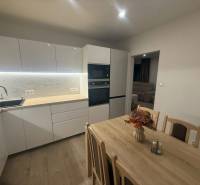 A kitchen in a 3-room apartment with bright lighting and a decorative wooden table.