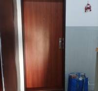 Wooden door leading to a one-room apartment with an entrance mat.