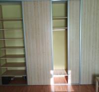 Built-in wardrobe with sliding doors and shelves, floor with wood decor in a studio apartment.