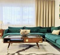 Family house with a green-toned sofa, wooden furniture, and art on the wall.