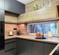 A kitchen in a family house with dark cabinets and a wood-patterned floor.
