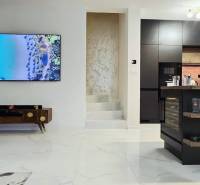 Living room in a family house with a fireplace and a kitchen island, floor with wooden decor.