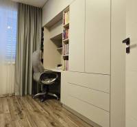 Study room in a family house with a work corner, white furniture, and a wooden decor floor.