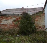A dilapidated brick wall and a neglected yard of a family house in Abrahám.