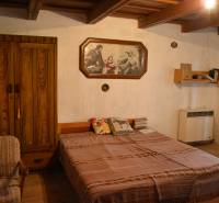 Bedroom in a family house with a wooden wardrobe, bed, and a picture on the wall.