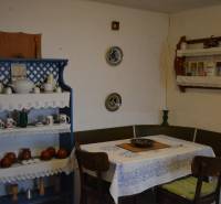 A dining room in a family house with a blue shelf and wooden furniture, decorated with dishes and a tablecloth.