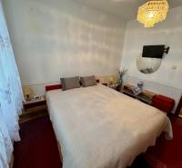 A bedroom in a 3-room apartment with a bed, a chandelier, and a TV on the wall.