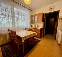 A kitchen in a 3-room apartment with a wooden decor, dining table, and curtains.