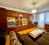 Living room with a rustic wall unit and TV in a three-room apartment.