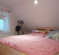An attic bedroom in a family house with a bed, television, and a wooden decor floor.
