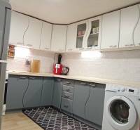 A kitchen in a family house with white and gray cabinets, a floor with a wooden decor.