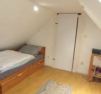 Attic room with a sloped wall, bed, and wooden decor flooring in a family house.