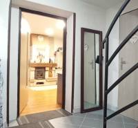 Interior of a family house with a staircase, wood-patterned flooring, and a fireplace.